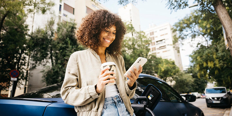 Woman holding a coffee cup in one hand and a phone in the other